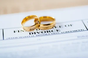 A piece of paper with Divorce written on it with two golden wedding bands.