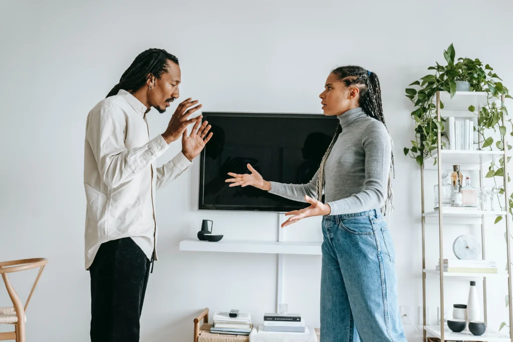 A married man and a woman verbally fight and look upset in their living room.