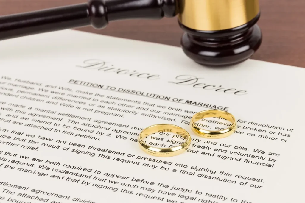 Divorce decree documents with rings and gavel.