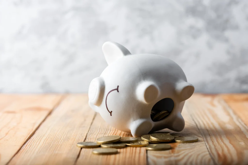 Tipped over piggy bank with coins.