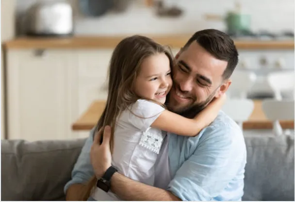 Dad smiling and hugging daughter.