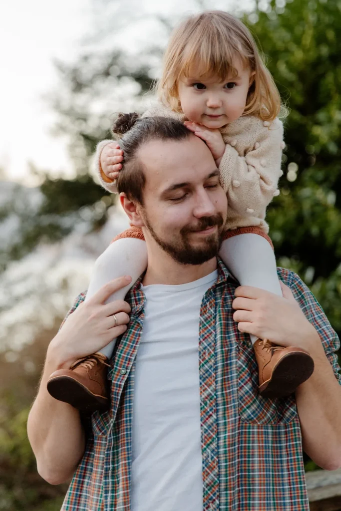 Smiling dad with daughter on his shoulders.