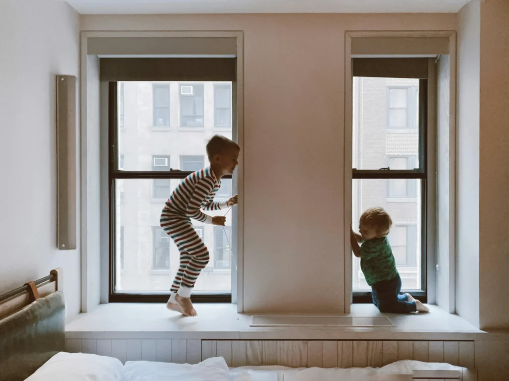 Two children playing by the window.