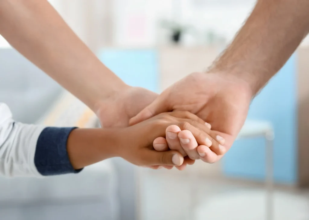 A close-up of adult hands gently holding a child’s hand, symbolizing the compassionate responsibilities of guardianship in Austin.