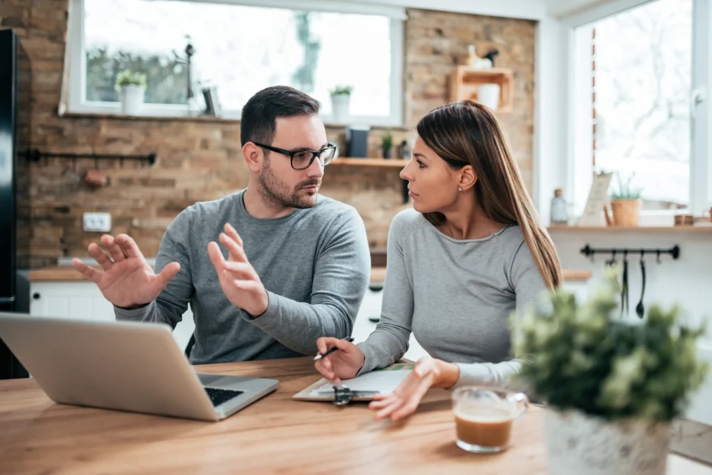 Concerned couple discussing co-parenting challenges at home with a laptop and documents during a custody planning session in Austin.