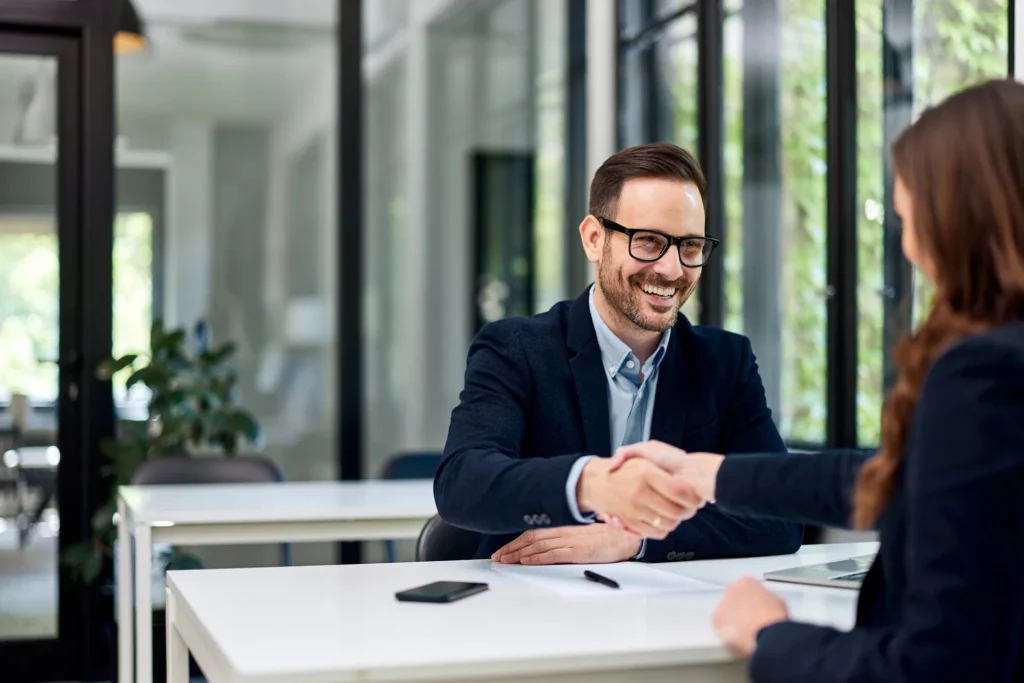 Smiling family law attorney shaking hands with a client during a co-parenting consultation in a modern Austin office.